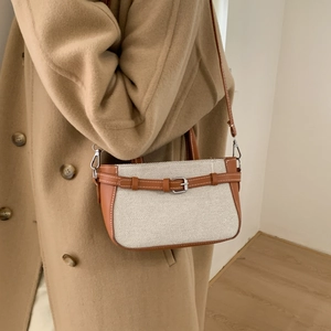 Vintage canvas and brown leather crossbody bucket bag shown on model in stylish autumn coat
