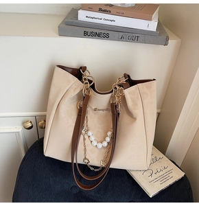 Detail of cream and brown tote bag with decorative pearl and gold flower chains