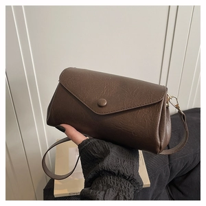 Detail of vintage dark brown faux leather crossbody bag with a round buckle and golden hooks