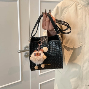 Détail du sac seau tressé noir avec inscription dorée et breloque alpaga en peluche