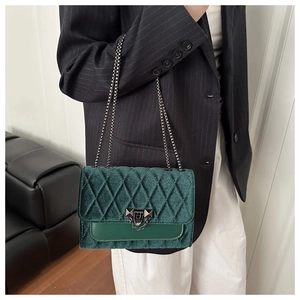 Detail of green velvet quilted bag featuring silver chain strap and metal fringe buckle
