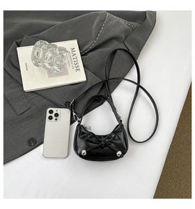 Détails du sac à main noir verni avec nœud et clous argentés sur un fond de studio élégant