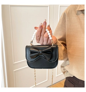 Detail of cute black mini bag with large leather bow and elegant white pearl handle