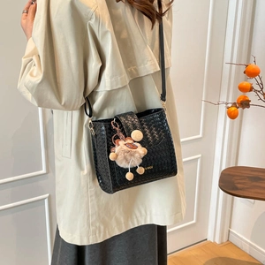 Retro black woven bucket bag with wide strap and plush charm shown on model