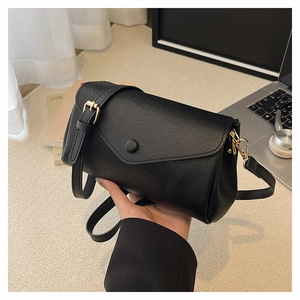 Detail of black crossbody bag with adjustable strap on a minimalist office desk