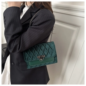 Detail of dark green quilted shoulder bag with chain strap and retro lock on model