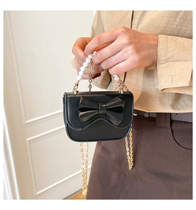 Dettaglio mini borsa nera con fiocco grande e manico di perle con tracolla a catena dorata