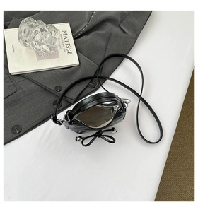 Détail du mini sac noir avec nœud, perles argentées et doublure grise à chevrons chic