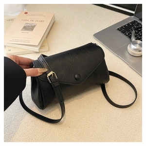 Detail of black matte pleated PU leather crossbody bag with adjustable gold metal buckle