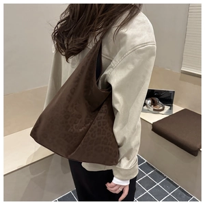 Chic leopard print hobo shoulder bag with velvet texture styled on a beige jacket model