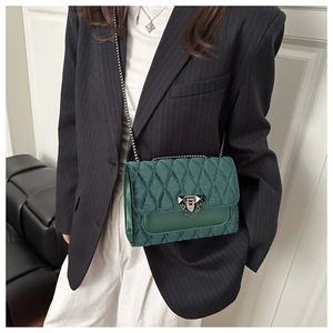 Detail of dark green velvet crossbody bag with diamond quilting and silver chain strap