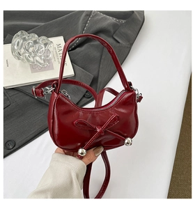 Détail du sac croissant rouge foncé avec nœud en cuir et détails de sphères argentées