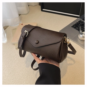 Detail of vintage brown pebble leather crossbody bag with adjustable strap and gold hardware