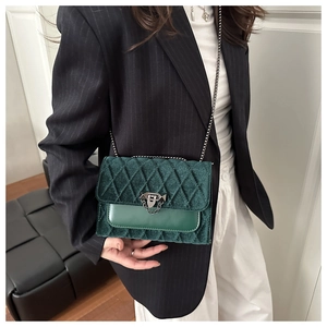 Detail of dark green crossbody bag featuring quilted velvet flap and silver chain strap