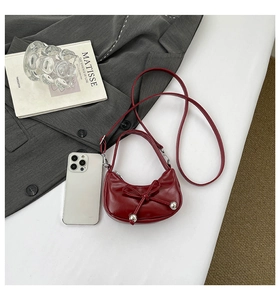 Vue de dessus du sac croissant rouge avec nœud et boules argentées sur blazer gris