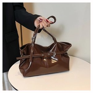 Detailed view of glossy dark brown leather tote bag with buckle strap and side pleats