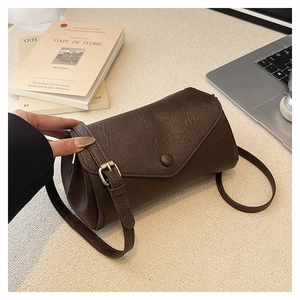 Detailed view of deep brown vintage crossbody bag on a desk with retro books