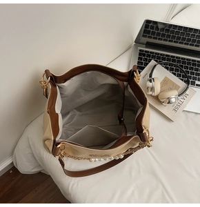 Detailed interior of a beige tote bag with a slip pocket and elegant pearl chain