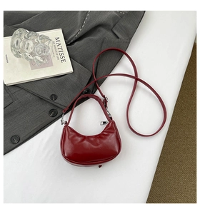 Vue détaillée du sac bandoulière rouge foncé en similicuir brillant de forme demi-lune