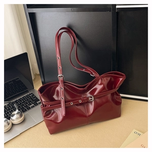 Detail view of burgundy glossy leather shoulder bag with adjustable belt buckles