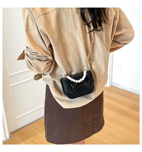 Dettaglio della mini borsa nera a tracolla con fiocco e manico di perle eleganti