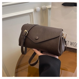 Close-up of dark brown lychee textured leather crossbody bag with vintage magnetic buckle