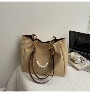 Detail view of a beige tote bag featuring pearl chain accents and Sunnycity branding