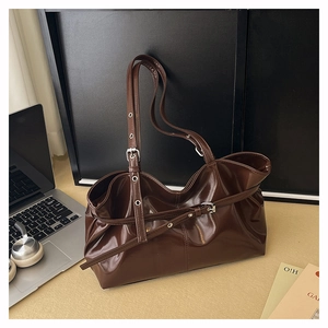 Detail of glossy dark coffee leather tote bag with side strap and metal buckle accent