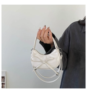 Gros plan d'un sac à main blanc en forme de croissant avec un nœud élégant