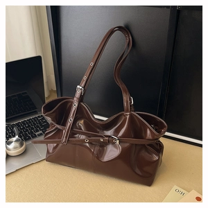 Detail of glossy coffee leather shoulder bag featuring adjustable buckle strap and polished texture