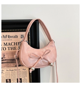 Détail du sac demi-lune en cuir verni rose avec nœud décoratif et perles argentées