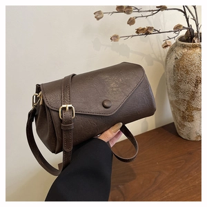 Detail of vintage brown textured leather handbag with envelope flap and adjustable strap