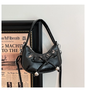 Détail du sac à nœud noir brillant avec perles argentées et bandoulière amovible