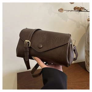 Detailed close-up of dark brown vintage leather crossbody bag with retro buckle detail