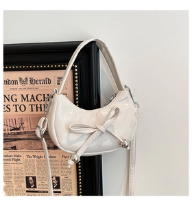 Détail du sac demi-lune en cuir verni blanc avec nœud et perles en métal argenté