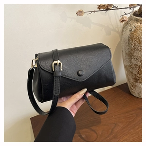 Detail shot of the black PU leather texture and golden metal buckle on the crossbody bag