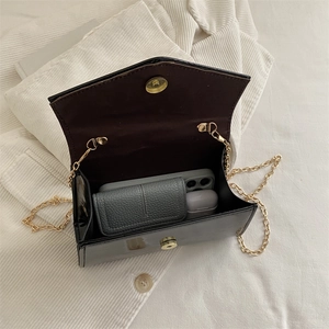 Glossy black patent leather flap bag with gold chain showing internal storage capacity