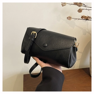 Detail of vintage black crossbody bag with lychee texture and gold buckle hardware