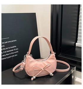 Détail de sac croissant rose avec nœud, perles argentées et texture en similicuir fin