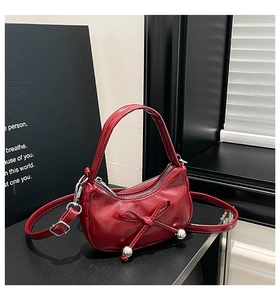Détail du sac en cuir verni rouge foncé avec nœud élégant et billes métalliques