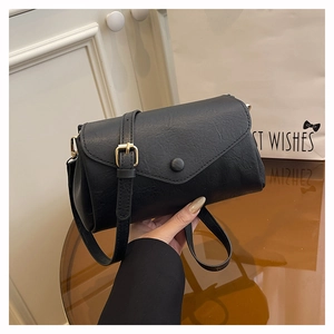 Close-up of black crossbody bag featuring pebble leather texture and gold hardware detail