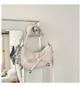 Détail du sac hobo crème avec nœud et perles argentées sur cuir brillant poli