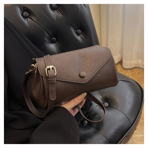 Detailed shot of dark brown vintage leather shoulder bag with gold adjustable buckle