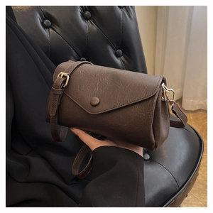 Close-up of deep brown lychee grain leather crossbody bag with gold-tone hardware detail