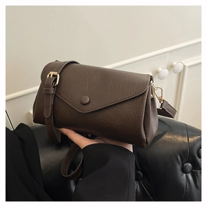 Detail of vintage brown crossbody bag with wide strap and gold metal hardware
