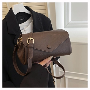 Detail of dark brown leather crossbody bag with golden metal adjustment buckle and strap