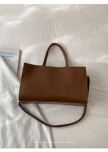 Top view of brown retro tote bag with dual handles and adjustable strap on white fabric