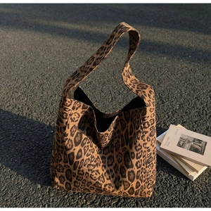 Gros plan détaillé sur la texture léopard en toile et la large bandoulière de ce sac cabas