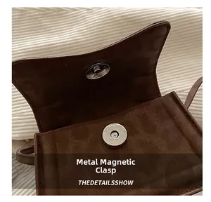 Dettaglio della chiusura magnetica in argento su borsa a tracolla in pelle scamosciata