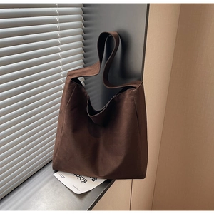 Détail du sac cabas marron foncé à texture mate posé contre un rebord de fenêtre